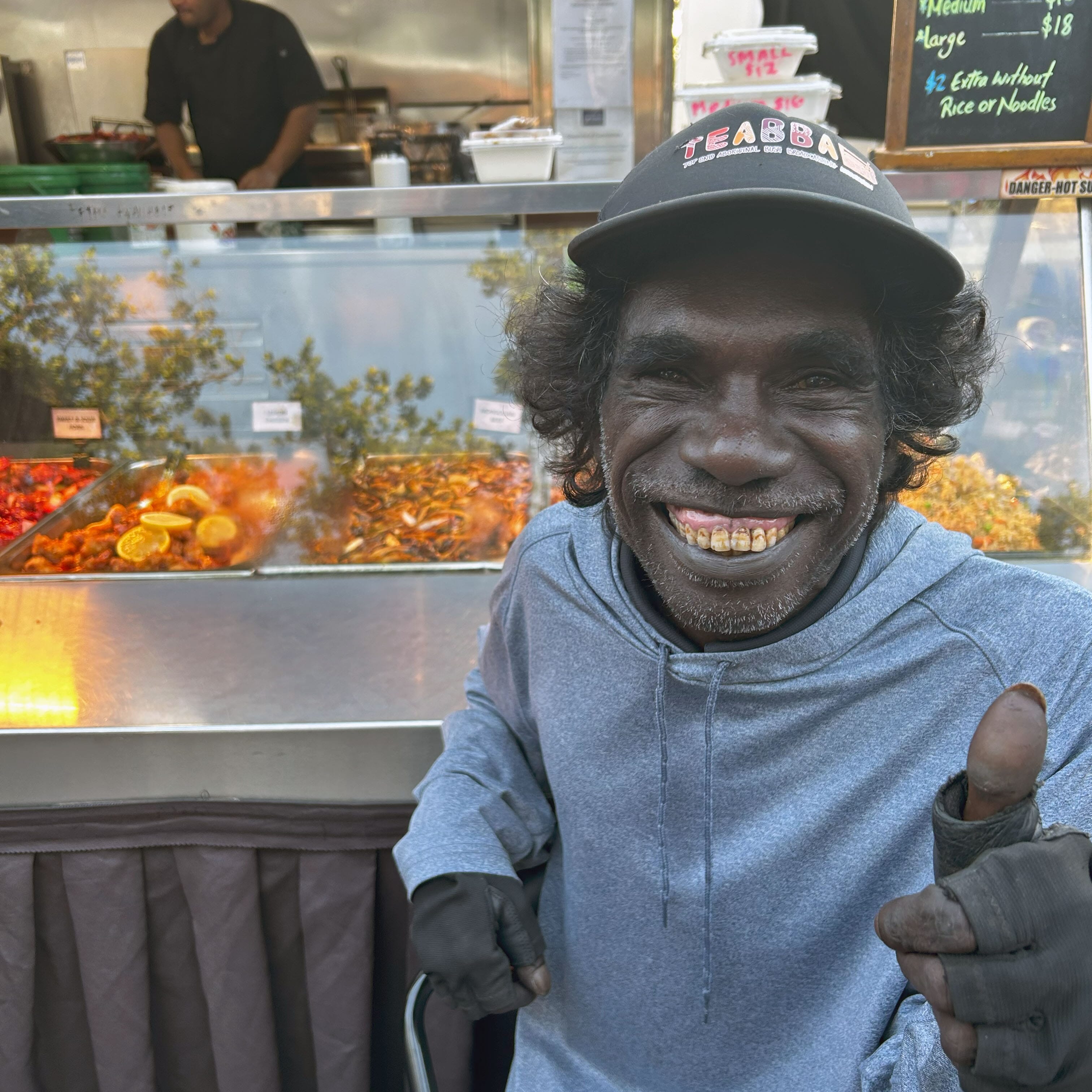 Jasco choosing dinner at Mindil Beach Markets in Darwin, smiling and giving a thumbs up.