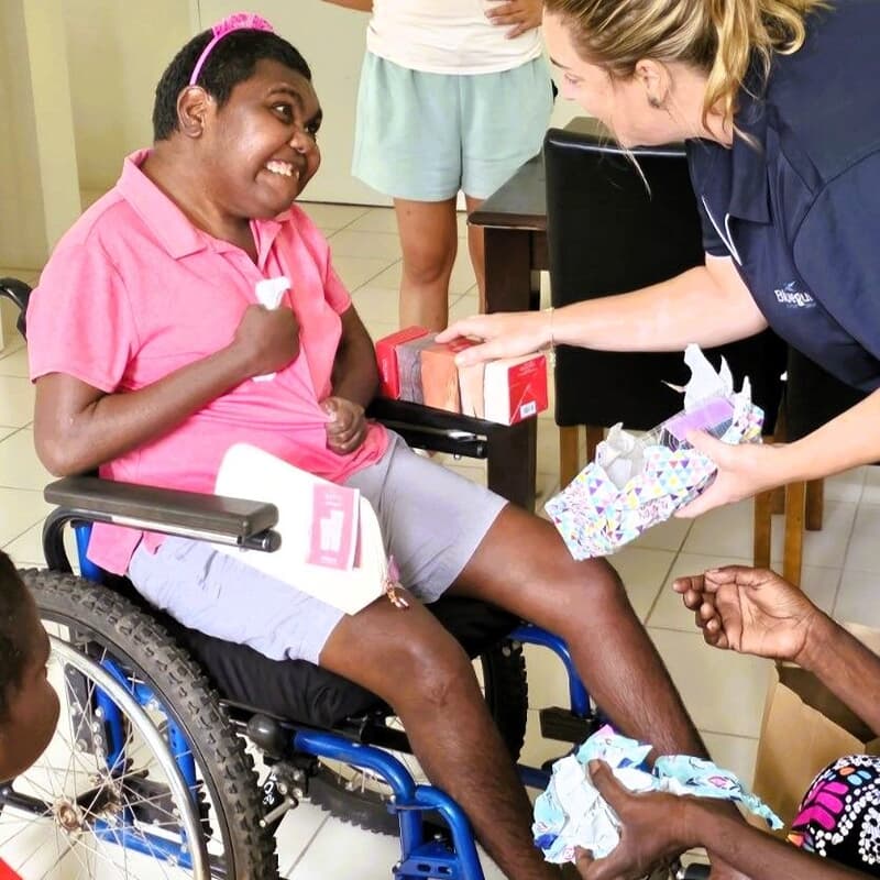 Participant opening birthday gifts at home with support.