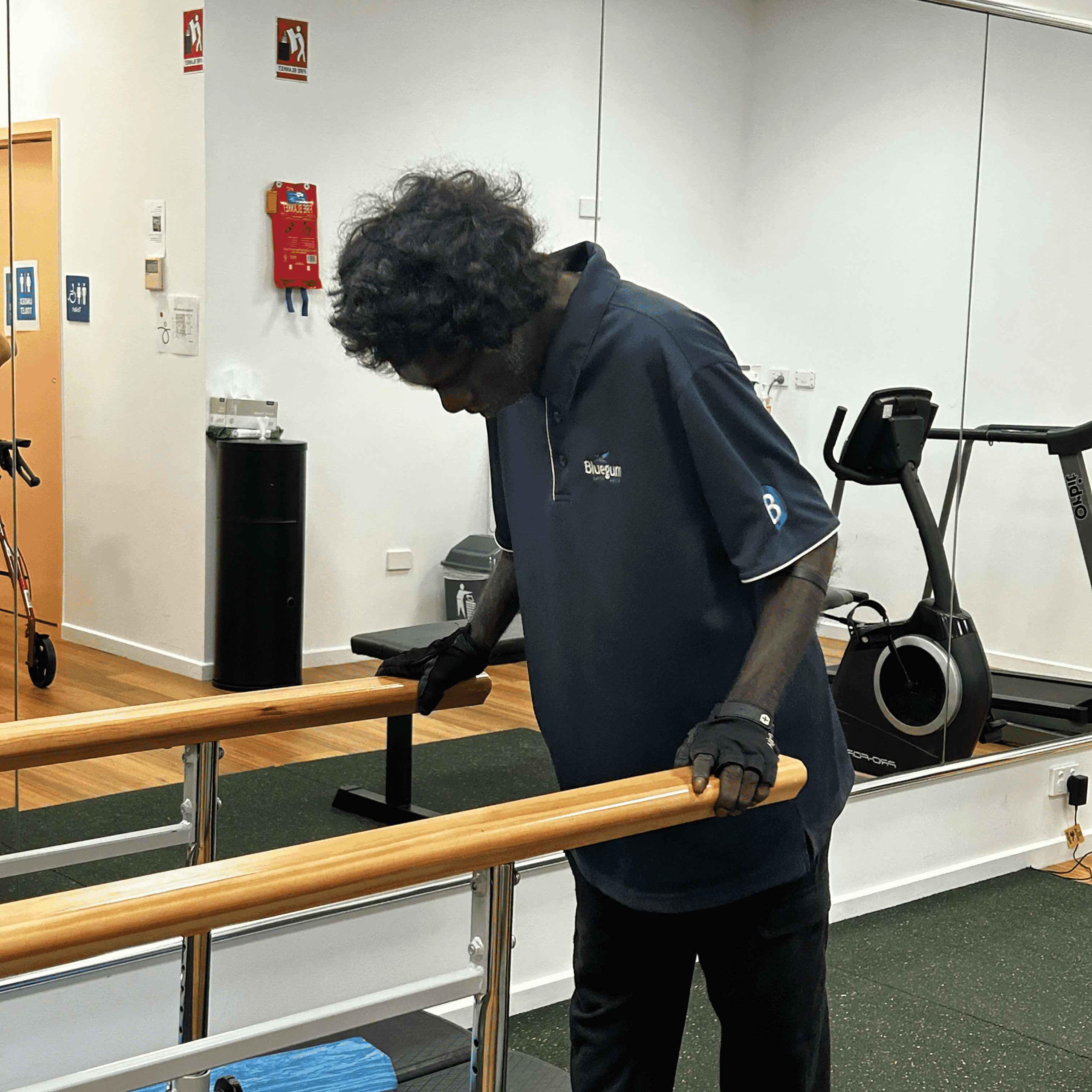 Jasko practises walking between parallel bars in a rehab gym, focusing on his balance and strength.