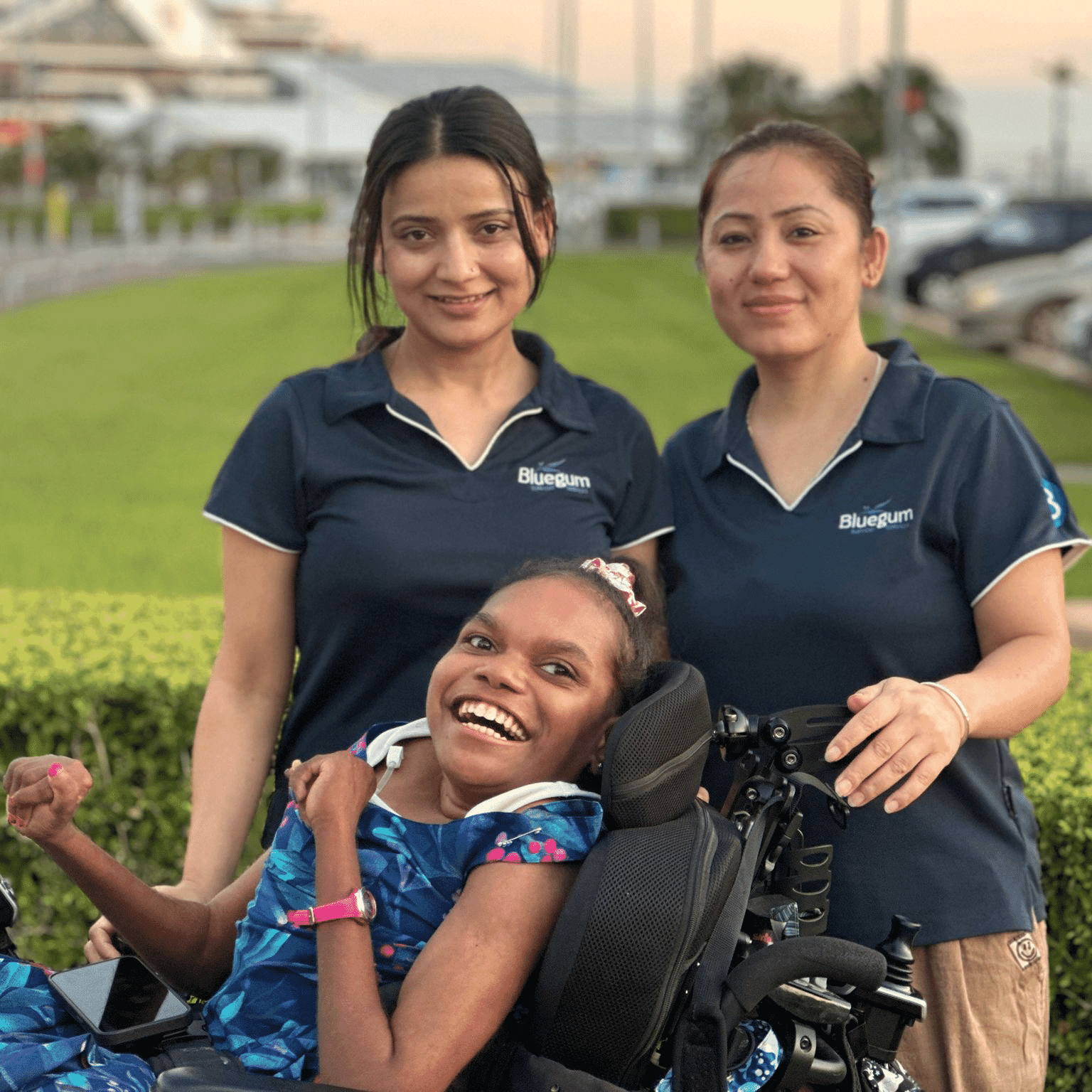 Stella smiling with two Bluegum support workers during a community access outing in Darwin.